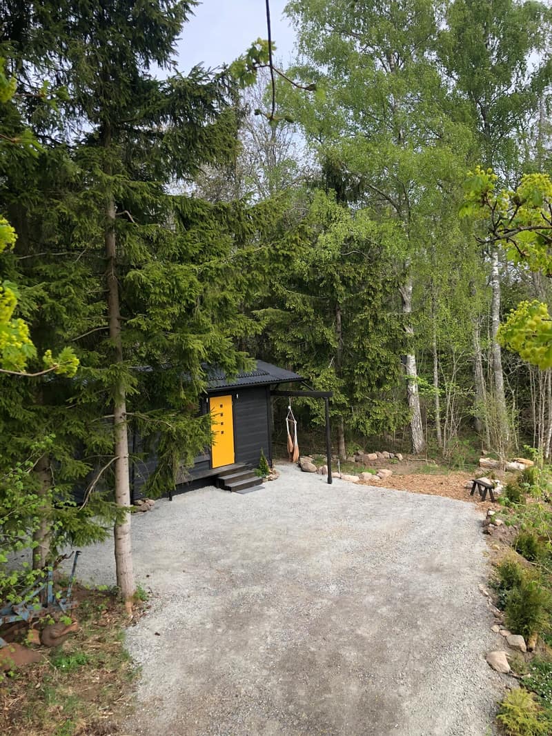 Den svartlaserade stugan med en bjärt gul dörr.